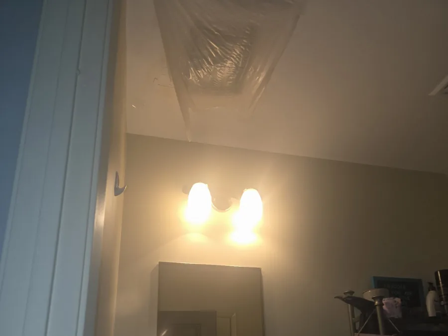 Bathroom ceiling with a plastic sheet taped over a damaged area