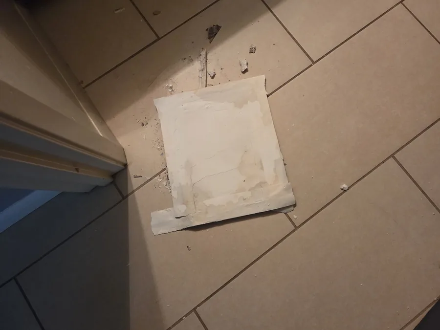 Plaster debris and a taped-up ceiling patch on the floor